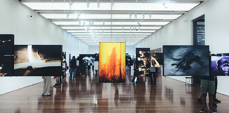 Una instal·lació artística a una sala ampla amb fotografies penjant de cables