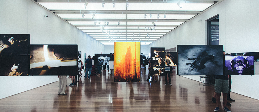 Una instal·lació artística a una sala ampla amb fotografies penjant de cables