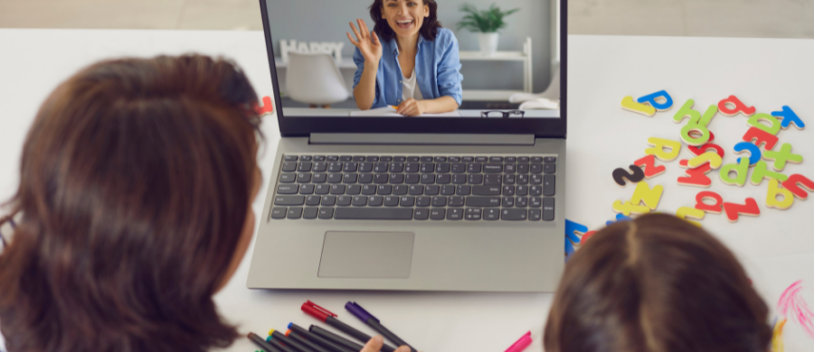 Nena seguint una classe virtual amb la professora a la pantalla