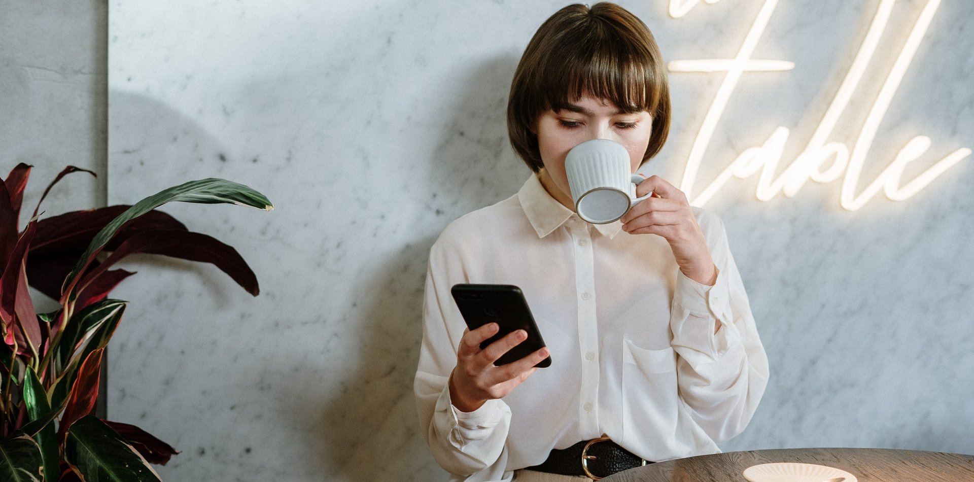 Mujer tomando un café mientras consulta el móvil