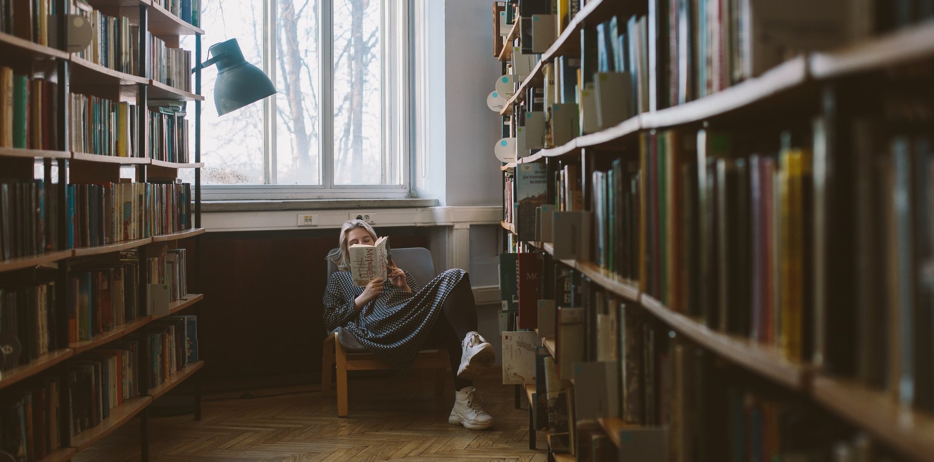 Mujer leyendo un libro sentada entre estanterías