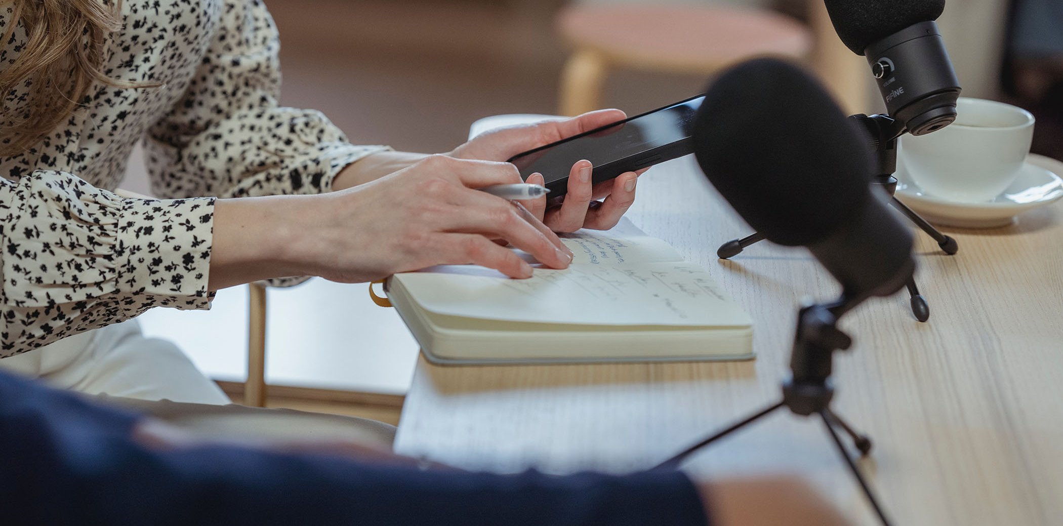 Periodista treballant amb una llibreta, un mòbil i un micròfon