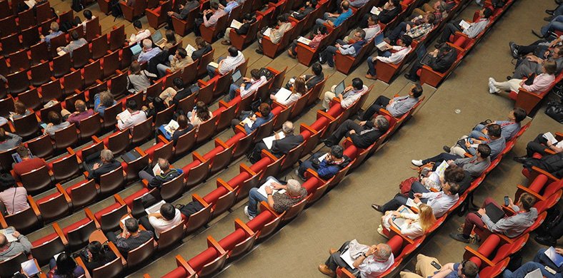 Diverses persones assegudes a les butaques d'un saló de congressos