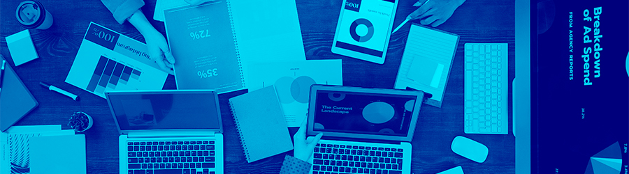 Varias personas con portátiles e informes de marketing alrededor de una mesa